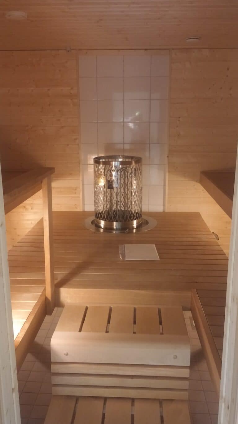 Vaaleat saunan lauteet, puupanelointi ja pyöreä pilarikiuas.