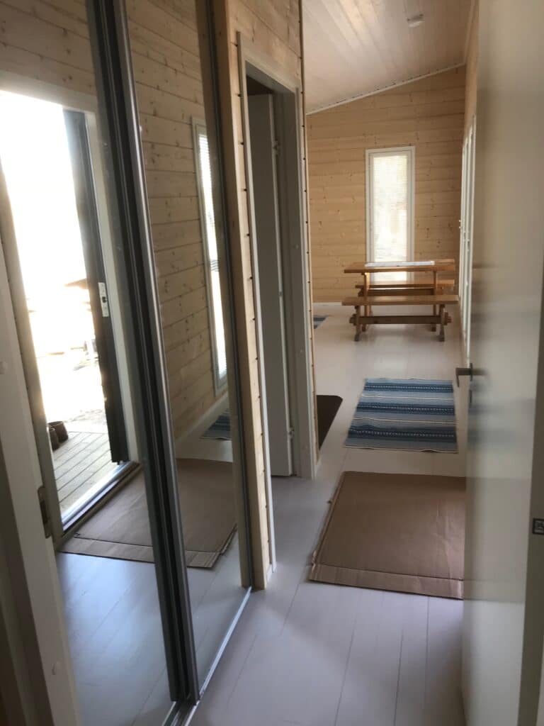 Peililiukuovet eteisessä ja näkymä puupintaiseen huoneeseen.